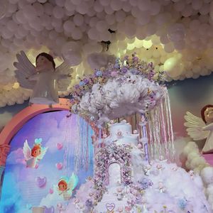 Bolo de aniversário de Maria Alice impressiona com 2,5 metros de altura, decorado com nuvens, flores e anjos, seguindo o tema celestial da festa