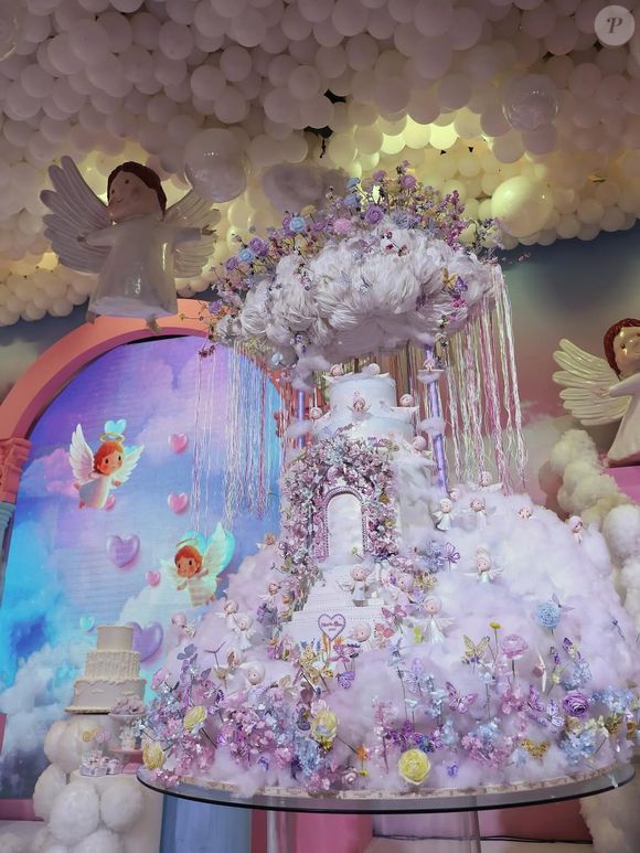 Bolo de aniversário de Maria Alice impressiona com 2,5 metros de altura, decorado com nuvens, flores e anjos, seguindo o tema celestial da festa