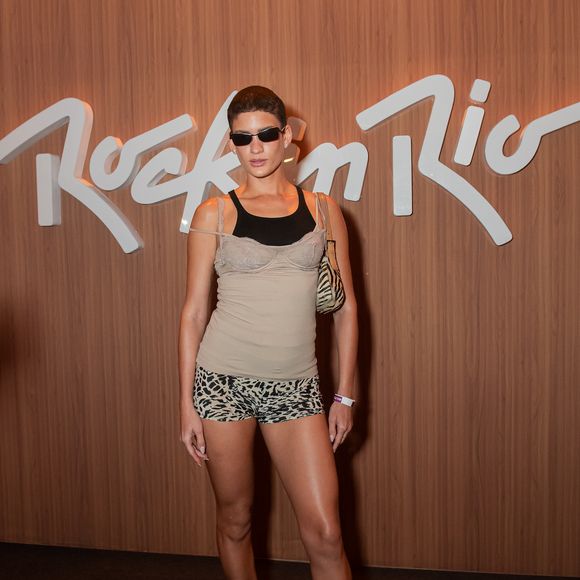 Laura Fernandes aposta em uma estética Y2K minimalista e sensual. A modelo combina uma regata bege sobreposta a uma peça preta com decote rendado estilo lingerie, acompanhada por hot pants em estampa de leopardo, chinelos de salto baixo, bolsa de ombro com estampa animal e óculos escuros de armação fina