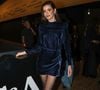 Camila Queiroz marcou presença com um vestido curto de veludo molhado em azul-petróleo. A peça, de mangas longas e gola alta, apresentava um discreto drapeado na saia e foi combinada com meia-calça preta fio 20 e sapatos de bico fino pretos com fivela no tornozelo