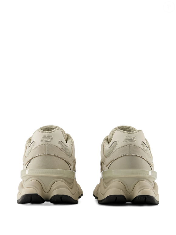 O New Balance 9060 com patch de logo une referências retrô e esportivas a detalhes sofisticados, como as sobreposições de camurça, criando um tênis que chama atenção sem depender de cores vibrantes