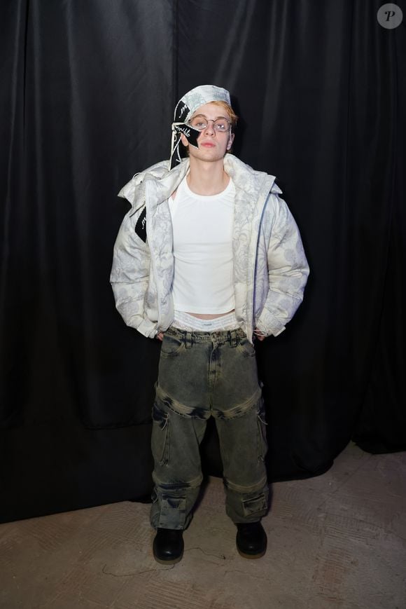 Juliano Floss ousou na escolha do look para prestigiar o evento fashion em São Paulo. Além da jaqueta puffer estampada e da calça jeans cargo de modelagem ampla, o influenciador deixou à mostra uma cueca branca de renda, criando um detalhe provocante na produção