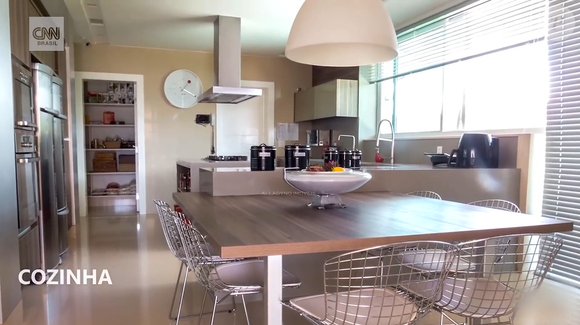 Cozinhas integram a estrutura da mansão, que também conta com espaço gourmet. A descrição do imóvel destaca uma residência planejada para reunir diferentes ambientes de convivência em seus mais de mil metros quadrados construídos.