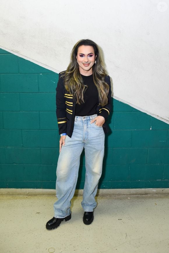 Andy Rodriguez apostou na sofisticação do estilo militar ao vestir um blazer preto estruturado com galões e listras douradas nas mangas. A peça sobrepôs uma camiseta preta básica, combinada com calça jeans clara em modelagem wide leg de cintura alta