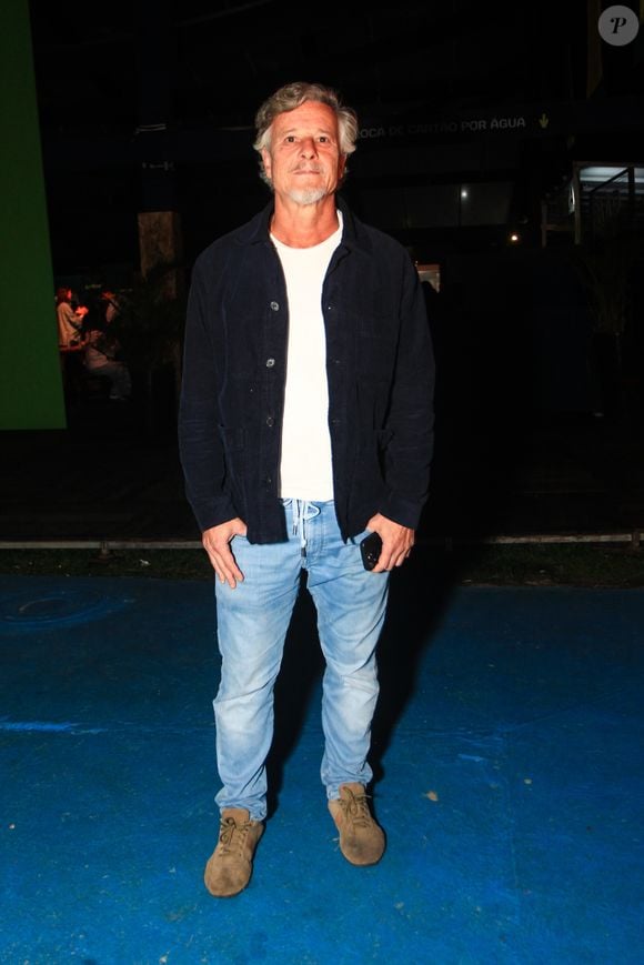 Marcello Novaes comparece ao evento com um visual casual e confortável, composto por uma jaqueta de veludo cotelê azul-marinho usada aberta sobre uma camiseta básica branca lisa. Para finalizar a produção descontraída, o ator veste uma calça jeans clara de lavagem estonada com amarração no cós e tênis casuais de camurça bege