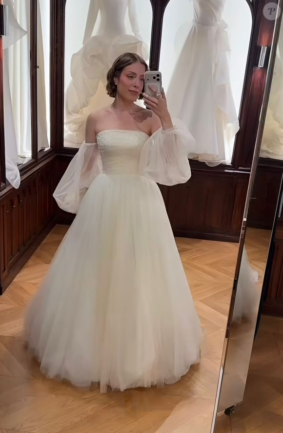 7. Princesa de tule com mangas bufantes soltas: vestido estilo princesa com corpete tomara que caia estruturado de acabamento liso e saia bem volumosa feita em camadas de tule. O visual é finalizado por mangas removíveis estilo ombro a ombro (off-the-shoulder), confeccionadas em organza/tule transparente com efeito bufante e punhos ajustados