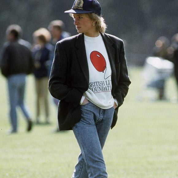 Em registros icônicos, como no clube de polo em Windsor, a princesa combinou jeans, moletom e boné com botas, criando um visual casual que segue inspirando gerações