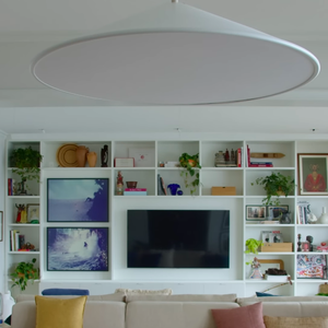 Sala de estar do casal conta com um sofá grande, muito espaço de interação e uma TV acoplada na parede