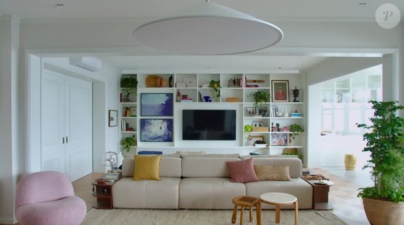 Sala de estar do casal conta com um sofá grande, muito espaço de interação e uma TV acoplada na parede