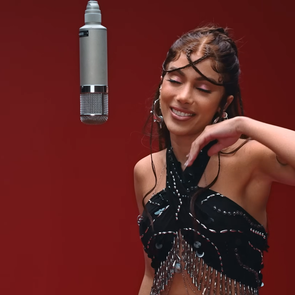 Mas o look da “Girl From Rio” não passou despercebido. Na parte superior, ela usa um top halter preto assimétrico, ricamente adornado com aplicações metálicas, franjas e pedrarias, criando movimento e brilho a cada gesto. Nos braços, braceletes metálicos esculturais reforçam a atmosfera tribal chic