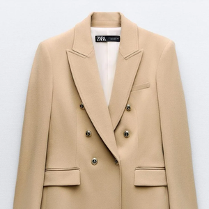 Em nossas buscas fashion, encontramos no Enjoei um modelo semelhante da Zara: blazer bege alongado, justo, cruzado com botões dourados, por R$ 380 na plataforma de desapego