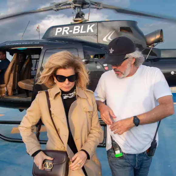 Na cena em que Odete Roitman desce do helicóptero no Brasil, é possível observar que ela usa uma roupa preta, trentch coat e bolsa de grife.
