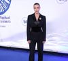Antes de surgir com a criação inspirada na literatura brasileira, Alice também passou pelo tapete azul usando um elegante conjunto de alfaiataria preta. O visual era formado por blazer de lapela acetinada, cintura marcada por uma larga faixa de veludo, calça reta e um maxi broche colorido aplicado no peito, combinação que antecipava a sofisticação da noite