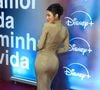 Bruna Marquezine: exibe o look por outro ângulo, destacando a fenda posterior sutil e a modelagem perfeitamente ajustada do vestido longo dourado com acabamento reluzente, além do coque alto elegante e sandálias de salto fino em tom metalizado
