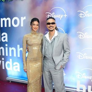 Bruna Marquezine e Sérgio Malheiros: Bruna surge deslumbrante em um vestido longo dourado de mangas compridas, gola alta e acabamento reluzente em paetês; Sérgio a acompanha com seu costume cinza amplo, colete e camisa branca de gola aberta