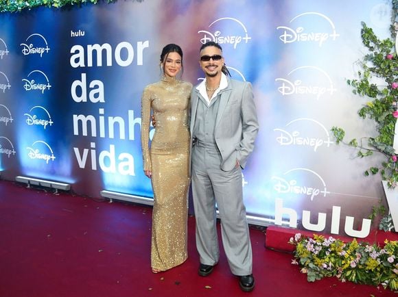 Bruna Marquezine e Sérgio Malheiros: Bruna surge deslumbrante em um vestido longo dourado de mangas compridas, gola alta e acabamento reluzente em paetês; Sérgio a acompanha com seu costume cinza amplo, colete e camisa branca de gola aberta