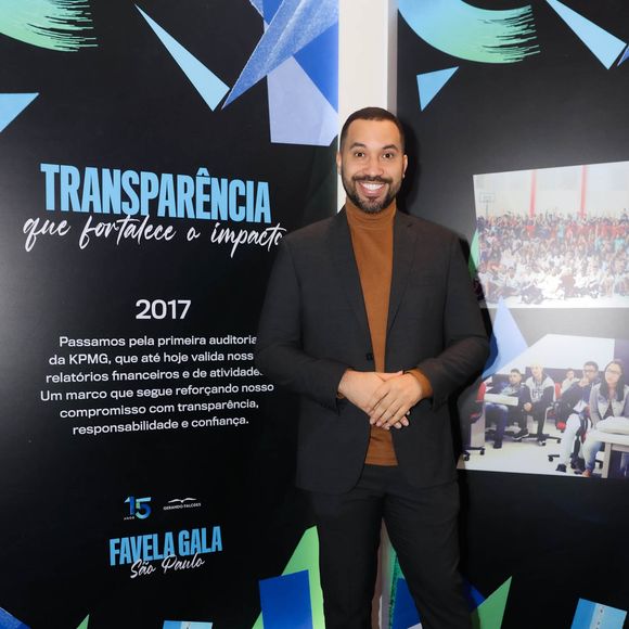 Gil do Vigor: sua produção aposta na sobreposição elegante de terno preto clássico com blusa de gola alta em tom marrom-terroso. O visual alinha o formal ao moderno, arrematado por sapatos sociais pretos de solado tratorado