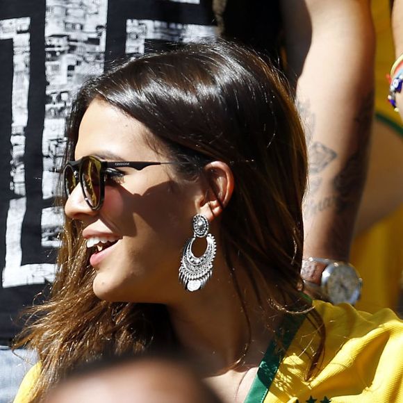 Brasilcore com toque boho chic? Bruna Marquezine já apostou na camisa da seleção combinada com calça jeans azul, óculos de sol e brincos que remetem à estética boêmia. O visual é uma ótima inspiração para quem quer torcer com estilo na Copa do Mundo de 2026