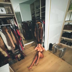 Ex-mulher de Kanye West, Kim Kardashian surgiu apenas com a parte de cima, sentada no clost, com as roupas em volta.