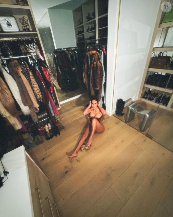 Ex-mulher de Kanye West, Kim Kardashian surgiu apenas com a parte de cima, sentada no clost, com as roupas em volta.