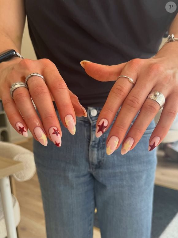Unhas estrelas sobre base natural: a combinação de nude com estrelas vermelhas e amarelas prova que uma manicure minimalista também pode ser cheia de personalidade nesta Copa