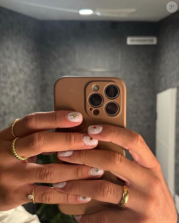 Nem todas as unhas de Jared McCain são maximalistas. O estilo Minimalista Celestial aposta em uma base leitosa transparente, conhecida como milky nails, acompanhada por pequenos brilhos em formato de estrela ou pontos de luz no centro da unha. É uma alternativa elegante e moderna para quem quer experimentar nail art sem abandonar um acabamento delicado