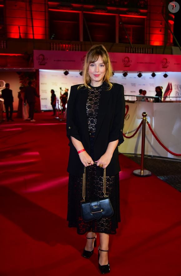 A atriz Malu Rodrigues apostou na tendência do 'dark romance'. Seu look consistiu em um vestido midi de renda preta trabalhada, com transparência sutil nas pernas e no colo. Por cima, um blazer preto alongado com mangas ¾ trouxe uma estrutura de alfaiataria ao visual. O toque final ficou por conta da bolsa Prada de couro preto com alça de corrente dourada e sapatos de bico quadrado com pulseira no tornozelo