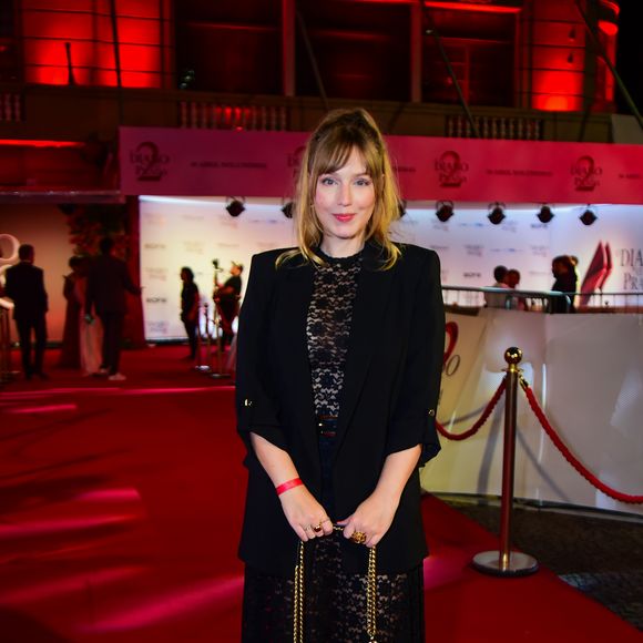 A atriz Malu Rodrigues apostou na tendência do 'dark romance'. Seu look consistiu em um vestido midi de renda preta trabalhada, com transparência sutil nas pernas e no colo. Por cima, um blazer preto alongado com mangas ¾ trouxe uma estrutura de alfaiataria ao visual. O toque final ficou por conta da bolsa Prada de couro preto com alça de corrente dourada e sapatos de bico quadrado com pulseira no tornozelo