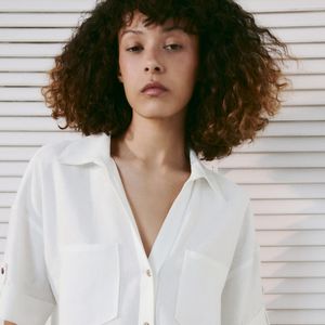 A Camisa Crop em Mistura de Linho com Botões da Zara tem modelagem cropped, gola de lapela, decote V, mangas curtas e dois bolsos de patch na parte frontal