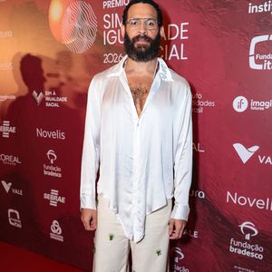 Drayson Menezzes optou por uma alfaiataria fluida e desconstruída em tons neutros. O ator veste um blazer oversized em tom areia sobre uma camisa de cetim marrom chocolate com gola pontuda aparente, criando um contraste elegante de texturas