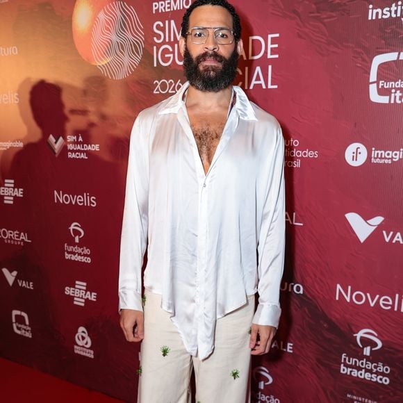Drayson Menezzes optou por uma alfaiataria fluida e desconstruída em tons neutros. O ator veste um blazer oversized em tom areia sobre uma camisa de cetim marrom chocolate com gola pontuda aparente, criando um contraste elegante de texturas