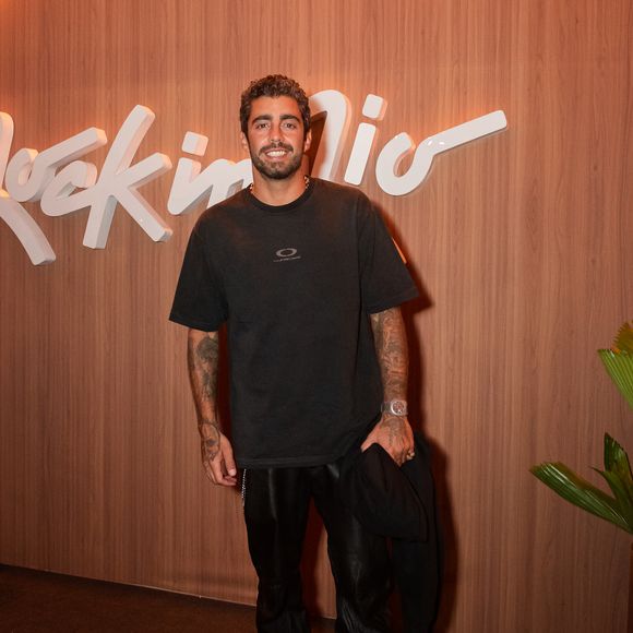 Pedro Scooby: o surfista investe na estética streetwear minimalista com uma camiseta preta oversized de malha encorpada e pequeno logotipo centralizado na altura do peito. Ele combina a peça com calça preta de couro de caimento reto, tênis pretos esportivos e relógio prateado de mostrador amplo, além de carregar uma jaqueta preta dobrada nas mãos