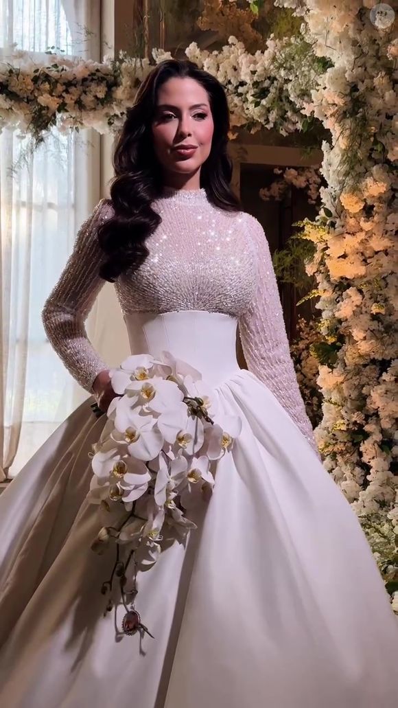 Look de noiva de Laís Caldas tem véu longo e buquê de orquídeas brancas, que dão o toque final de romantismo