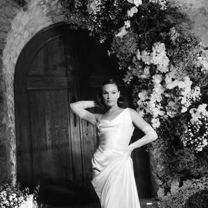 Vestido de Isis Valverde traz um decote torcido assimétrico, com drapeados suaves que caem sobre o corpo e se estendem até a cauda