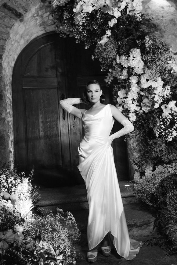 Vestido de Isis Valverde traz um decote torcido assimétrico, com drapeados suaves que caem sobre o corpo e se estendem até a cauda