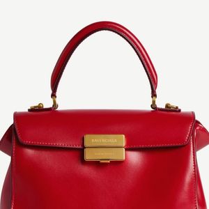 O look de Virginia foi complementado por bolsa de mão estruturada vermelha com fecho dourado e sapatos vermelhos de salto alto