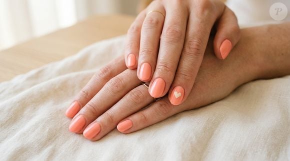 Pintar todas as unhas de coral e acrescentar um minúsculo coração em uma delas transforma uma proposta clássica em uma manicure delicada e personalizada