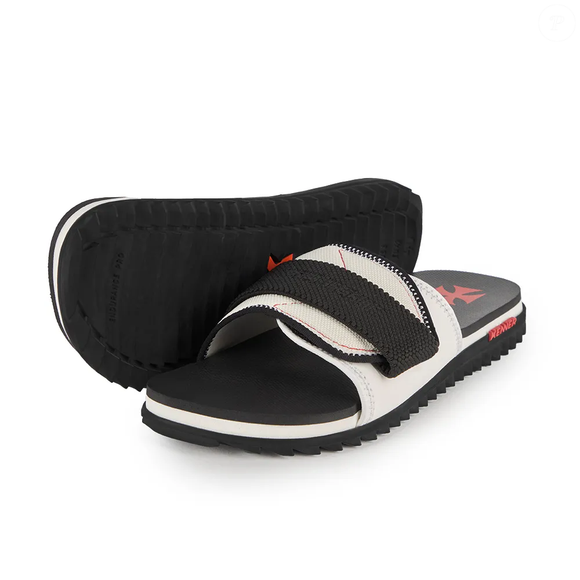 A nova sandália da Kenner apresenta cabedal de neoprene nas cores branca e preta, com pesponto contrastante vermelho, além de fechamento em velcro ajustável para adaptar o calçado aos pés