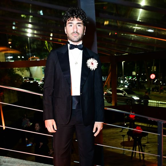 José Condessa: o ator português adotou um tuxedo clássico. O traje inclui um paletó preto com lapelas em cetim, calça de alfaiataria de corte reto com faixa na cintura (cummerbund) e camisa social branca com gravata-borboleta preta. O destaque do visual fica para o arranjo floral de flor branca aplicado na lapela