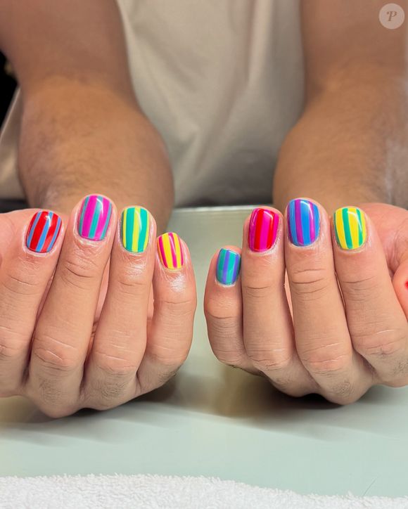 Para as fãs de cores vibrantes, o Maximalista Neon / Dopamine Brights é uma das opções mais chamativas. A nail art trabalha com blocos de cores vivas e listras verticais em neon, passando por rosa, azul, verde, amarelo e vermelho. É aquele tipo de unha que praticamente dispensa outros acessórios para ganhar protagonismo no visual