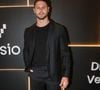 Jonas Sulzbach investe em um visual all black minimalista e contemporâneo, no melhor estilo esporte fino. Ele combina uma camiseta preta básica de gola careca com um blazer preto estruturado que possui uma sutil textura quadriculada ou jacquard no tecido, conferindo profundidade à peça. A calça de alfaiataria preta possui corte reto e caimento sob medida. Para quebrar a sobriedade monocromática e conferir um ar urbano e jovial à produção, Lucas finaliza o conjunto com tênis de couro totalmente brancos e de solado reto