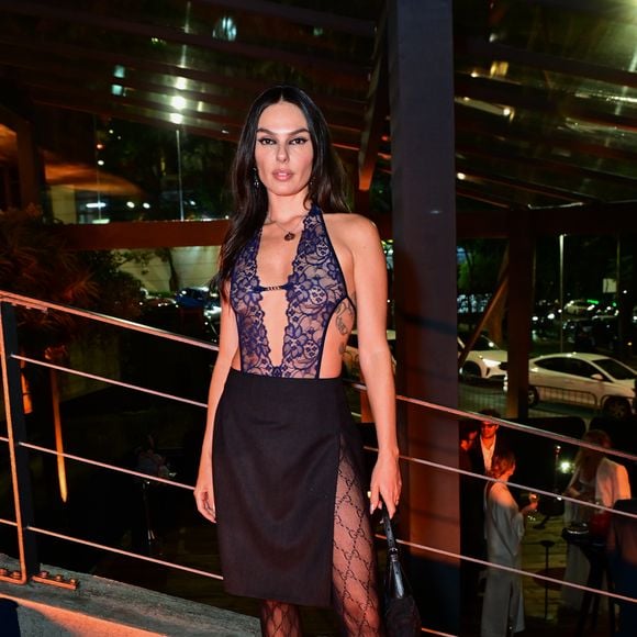 Isis Valverde: a atriz optou por um body frente-única em renda guipir azul-marinho com transparências e decote profundo, combinado com uma saia preta envelope de comprimento midi com fenda lateral. O look inclui meia-calça preta com monograma estilizado "GG", scarpins pretos de salto fino e uma bolsa pequena de ombro