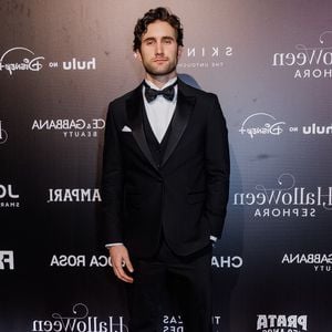 Felipe Ricca: o visual formal aposta em um tuxedo tradicional de três peças na cor preta, composto por paletó com lapela de cetim, colete ajustado e calça social de alfaiataria. A composição inclui camisa social branca com botões escuros, gravata borboleta preta, lenço de bolso branco dobrado e sapatos sociais pretos brilhantes