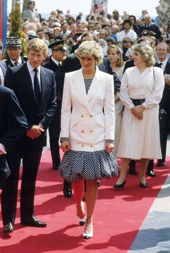 Em 1987, durante desembarque na Riviera Francesa, a eterna Princesa de Gales surgiu usando o modelo em uma produção assinada por Catherine Walker, composta por vestido mídi balonê listrado e blazer branco trespassado com ombros marcados