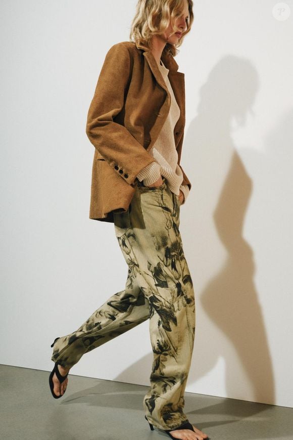 A calça jeans da Zara, com preço de R$ 439,00, aposta em uma estampa inspirada nos tapetes persas, tendência que acrescenta uma pegada vintage às produções. A peça pode ser combinada com os tênis bordô On Running Cloud 6 para criar um look casual com personalidade