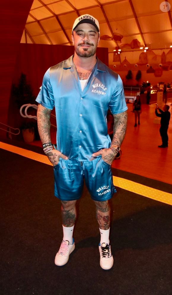 Felipe Titto escolheu um conjunto coordenado em cetim azul-turquesa com acabamento acetinado, composto por camisa de manga curta com gola bowling e bermuda com estampa Miracle Academy. Ele arrematou o visual sportswear com boné aba curva dos New York Yankees, meias altas e tênis casual
