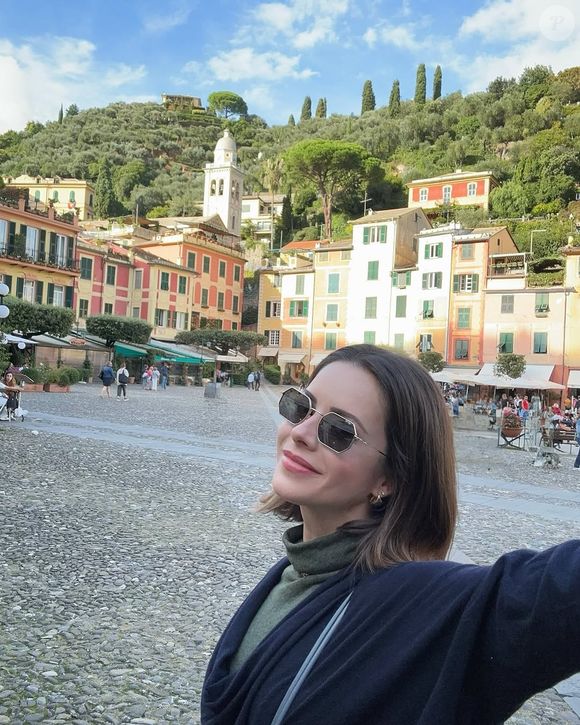 Sandy aparece discretamente no canto da tela, sem saber que a câmera a enquadrava