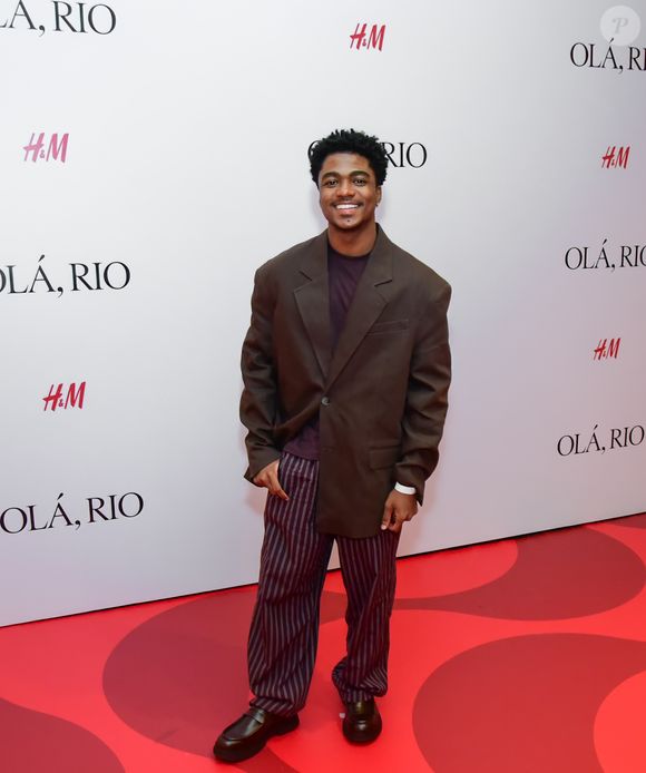 Guthierry Sotero: o ator investiu em um visual de proporções amplas e tons terrosos. A peça central é um blazer oversized marrom de abotoamento simples, usado sobre uma camiseta em tom de berinjela escuro. A parte inferior traz uma calça de alfaiataria com padronagem risca de giz em tons de vinho e cinza, com modelagem solta