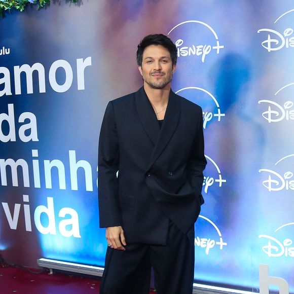 Rômulo Estrela: apresenta uma proposta moderna de alfaiataria em um terno risca-de-giz azul-marinho de modelagem oversized, com paletó transpassado de caimento solto e calça pantalona ampla, completando a produção com sapatos pretos de sola tratorada