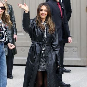 A atriz Jessica Alba sendo simpática em look all black com sobretudo preto na Semana de Moda de Paris 2025.